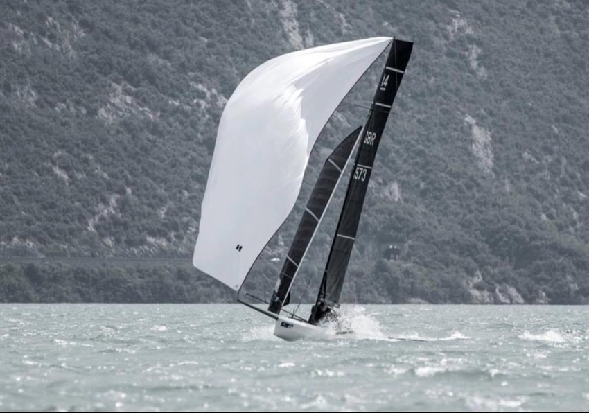 A racing dinghy sailing under spinnaker on Lake Garda